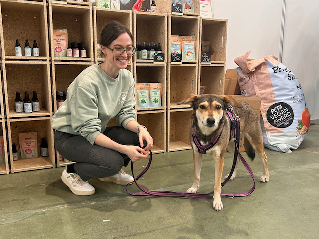 Sunna Becker von NOMS+ mit einem vierbeinigen Besucher am Stand